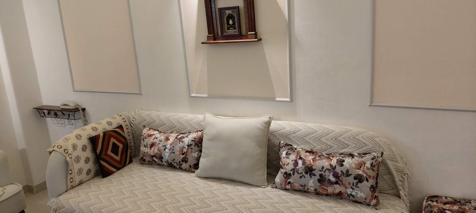 Sofa with cushions and small mandir on the wall